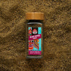 Sri Lankan Black pepper powder in a glass jar with ground black pepper in the background — Buy single origin spice from Raksha online.