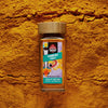Sri Lankan turmeric powder in a glass spice jar with single-origin ground turmeric scattered in the background