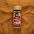 Ceylon Cinnamon powder in a glass spice jar with single-origin ground Cinnamon scattered in the background