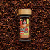 Whole Sri Lankan cloves in a glass spice jar with loose cloves scattered in the background